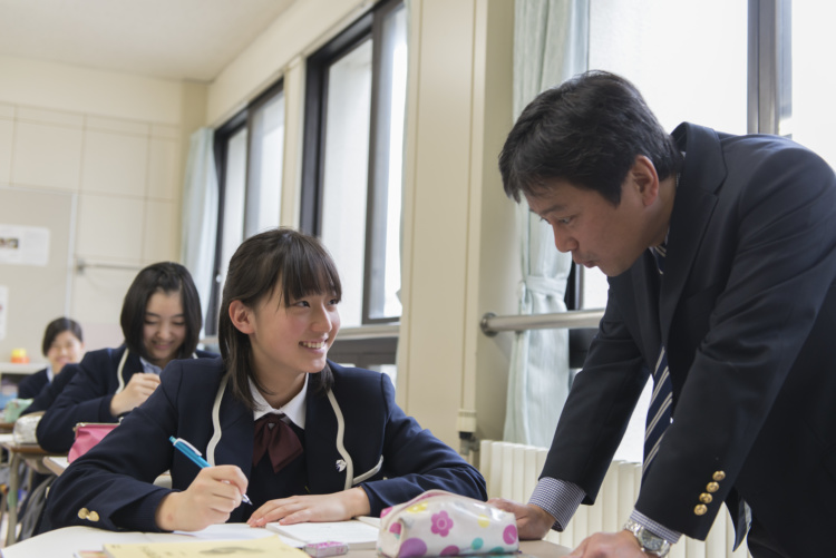 聖セシリア女子中学校・高等学校の授業で先生から指導を受ける女子生徒