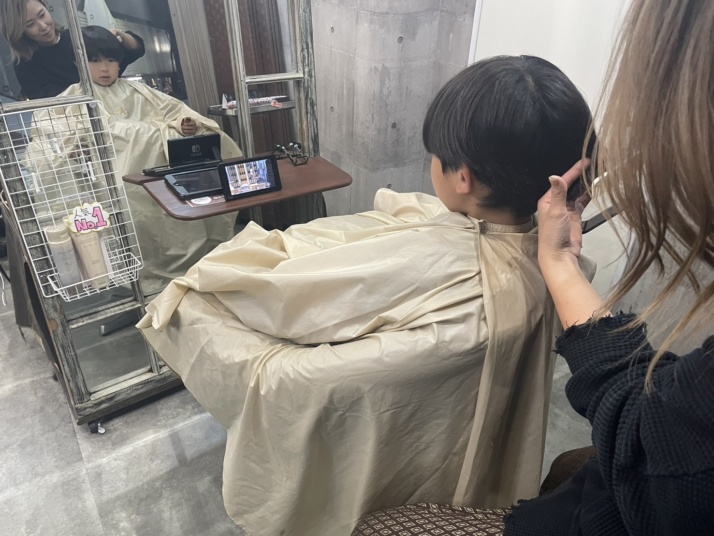 ヘアリゾートエーアイ北千住店でキッズカットを受けている子ども（動画視聴）