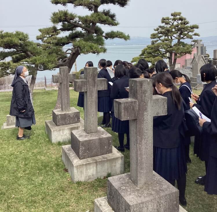 創立者墓参を行う函館白百合学園中学校・高等学校の生徒たちと教員