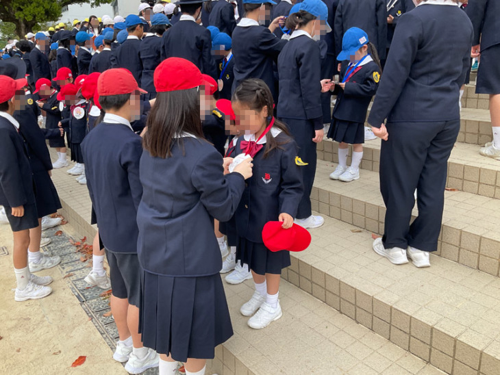 雲雀丘学園小学校の6年生が1年生に手作りのメダルをかけるようす