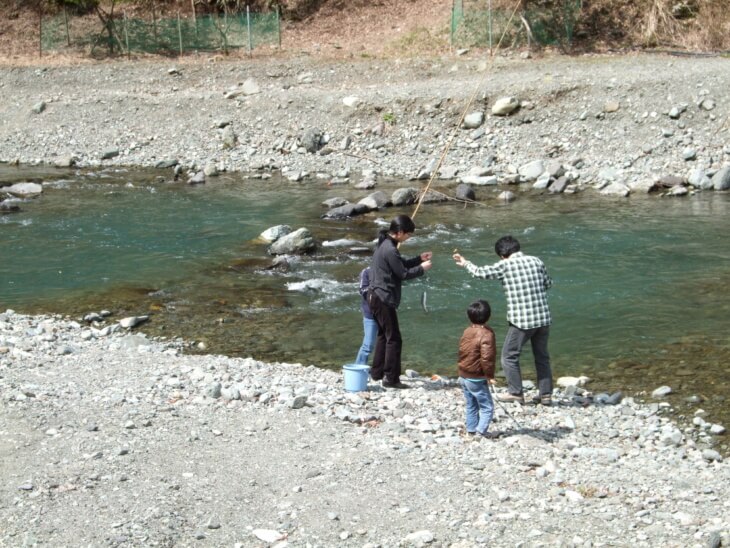 神奈川県相模原市にある「神之川キャンプマス釣り場」で魚釣りをする家族