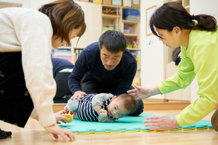 くぼたのうけんのスタッフや保護者に助けられらながら寝返りを打つ赤ちゃん