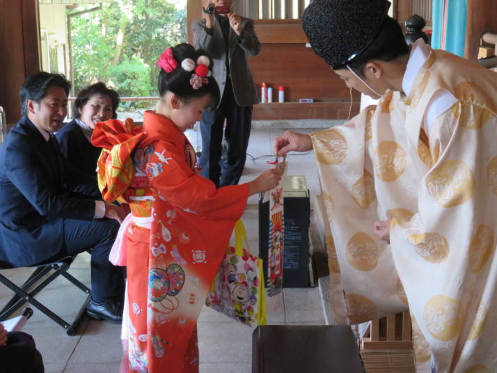 物部神社の七五三詣の御祈祷の最後に神職から御撤供品と千歳飴を受け取る子ども