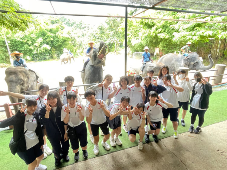 武庫川女子大学附属中学校・高等学校の生徒たちが海外研修先のタイでゾウと記念撮影する様子