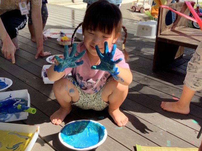 神奈川県横浜市の瀬谷区地域子育て支援拠点「にこてらす」で手に絵の具を付けて喜んでいる女の子