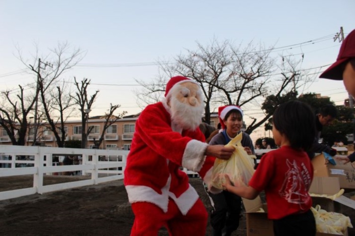 「ポニースクールかつしか」のクリスマスホースショーでお菓子をプレセントされる子ども