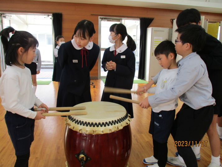 小学生が幼稚園児に太鼓を教えるようす