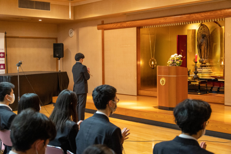 崇徳中学校・高等学校の講堂で阿弥陀如来に手を合わせる生徒たち