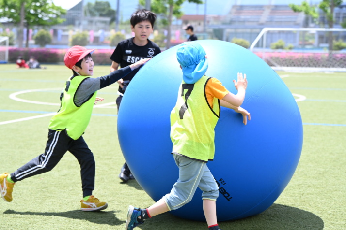 山梨学院小学校の児童が大きなボールを転がすようす